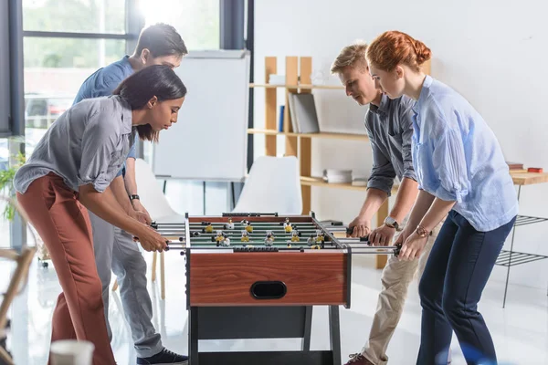 Colegas jugando futbolín en la oficina moderna - foto de stock