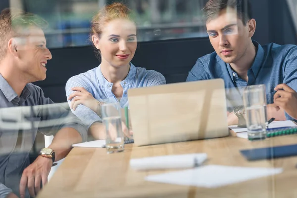 Behind the glass view of young team discussing project in modern office — Stock Photo