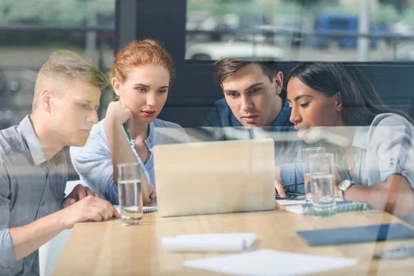 Derrière la vue en verre des gens d'affaires concentrés discutant du projet dans le bureau moderne — Photo de stock