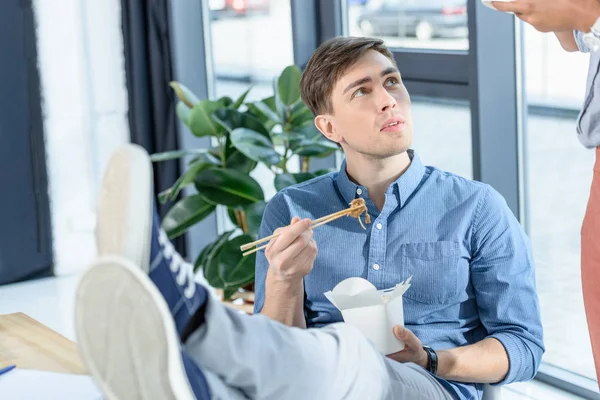 Young businessman eating chinese food during meeting break in modern office — Stock Photo