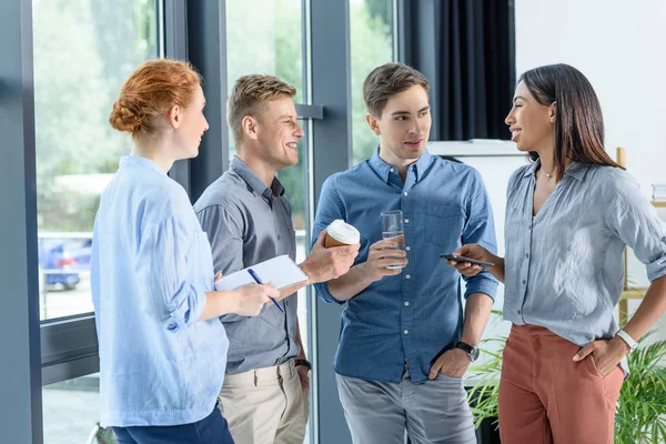 Jóvenes empresarios discuten proyecto en oficina moderna - foto de stock