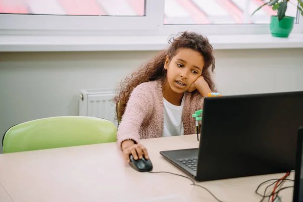 Ennuyé afro-américaine écolière travaillant avec ordinateur à l'école — Photo de stock