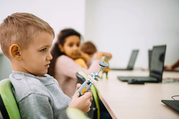 Side view of serious little kid with diy robot — Stock Photo