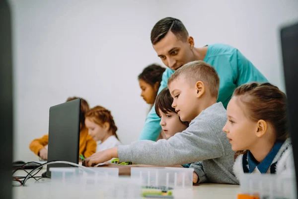 Niños que trabajan con el profesor en su proyecto de educación robótica - foto de stock