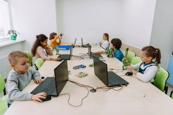Grupo de niños enfocados que trabajan con computadoras en clase de maquinaria - foto de stock