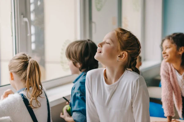 Adorable schoolchildren looking at window together at classroom — Stock Photo