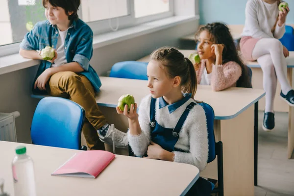 Adoráveis crianças em idade escolar comendo maçãs na sala de aula durante a pausa — Fotografia de Stock