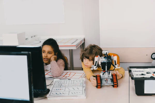 Niños exhaustos que trabajan con la computadora para programar robot, concepto de educación del vástago - foto de stock