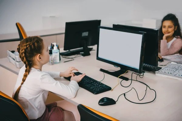 Schoolgirls working with computers at classroom together — Stock Photo