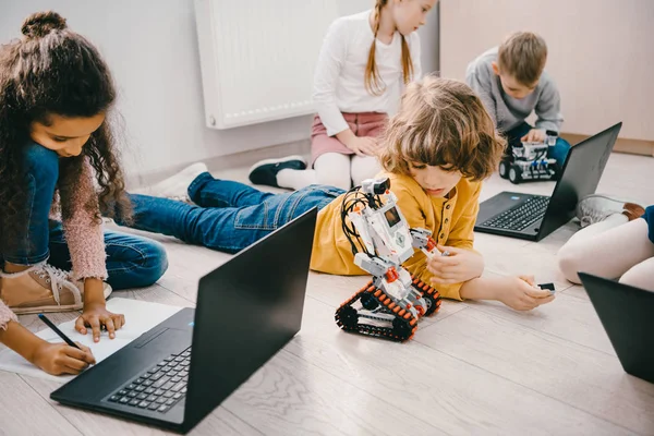 Little kids programming with laptops while sitting on floor, stem education concept — Stock Photo