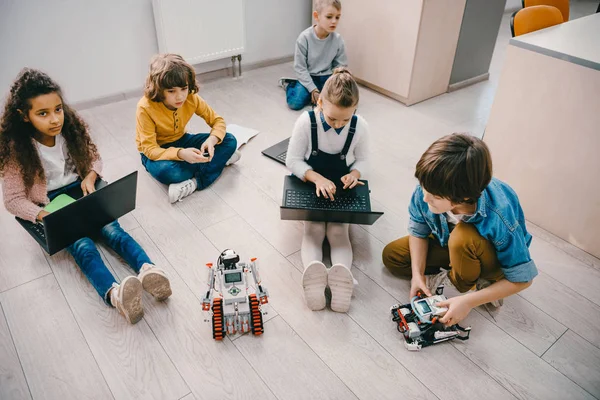High angle view of kids programming robot while sitting on floor at stem education class — Stock Photo