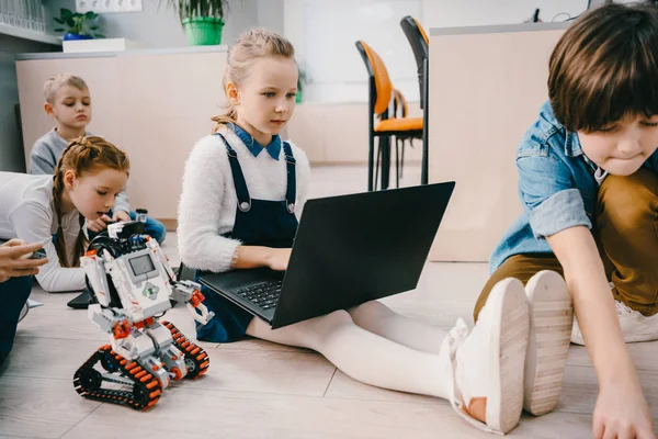 Kids programming robot while sitting on floor at stem education class — Stock Photo
