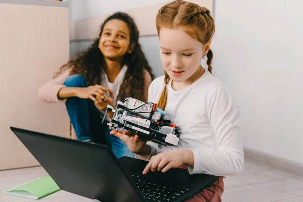 Teen schoolgirls programming robot while sitting on floor — Stock Photo