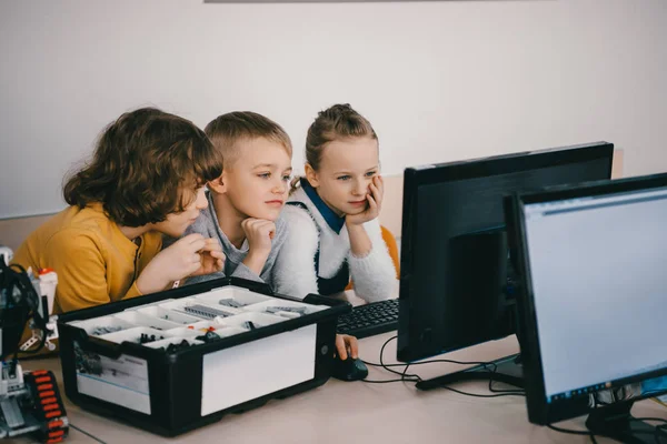 Сфокусированные дети, работающие вместе с компьютером, концепция базового образования — стоковое фото