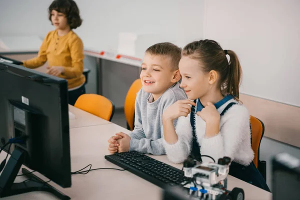 Niños felices trabajando juntos con la computadora en la clase de maquinaria - foto de stock