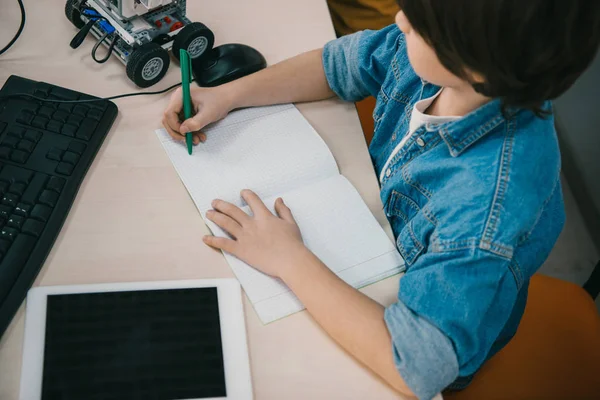 High angle view kid writing in notebook at machinery class — Stock Photo