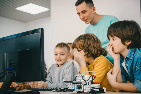 Teacher programming robot with his teen students — Stock Photo