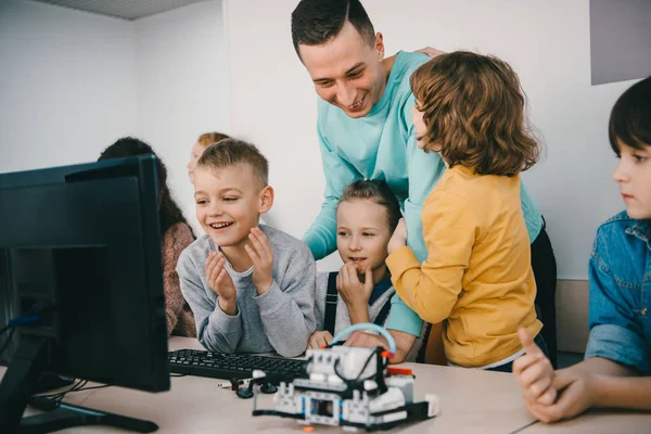 Profesor ayudando a sus estudiantes adolescentes con robot bricolaje en la clase de educación del tallo - foto de stock