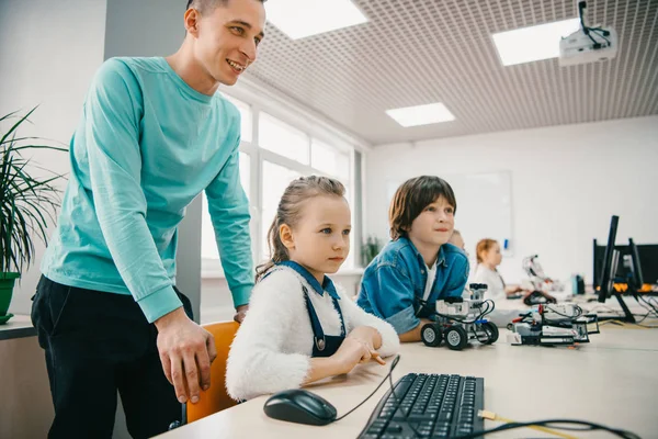 Young teacher helping his teen students with diy robot on stem education class — Stock Photo