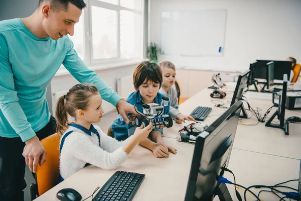 Teacher helping his teen students with diy robot on stem education class — Stock Photo
