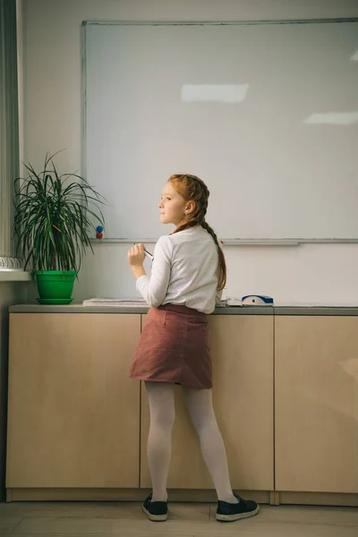 Adorable little schoolgirl standing in front whiteboard — Stock Photo