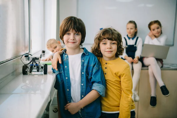 Happy little kids with diy robot embracing on machinery class — Stock Photo