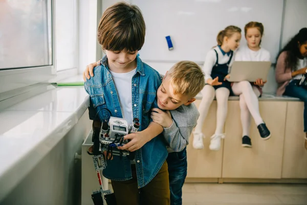 Niños pequeños con robot bricolaje abrazando en la clase de maquinaria - foto de stock