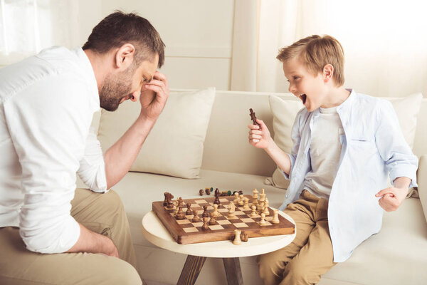 boy playing chess with father