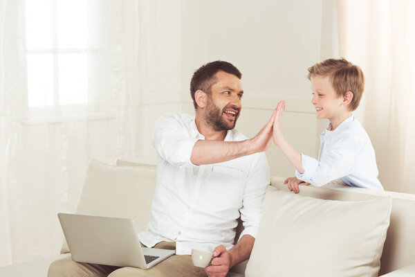 father giving high five to son