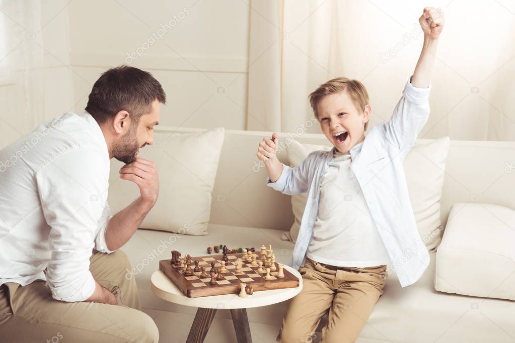 boy playing chess with father