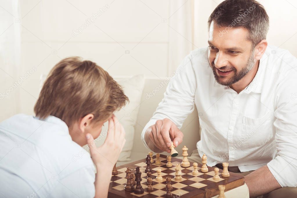boy playing chess with father