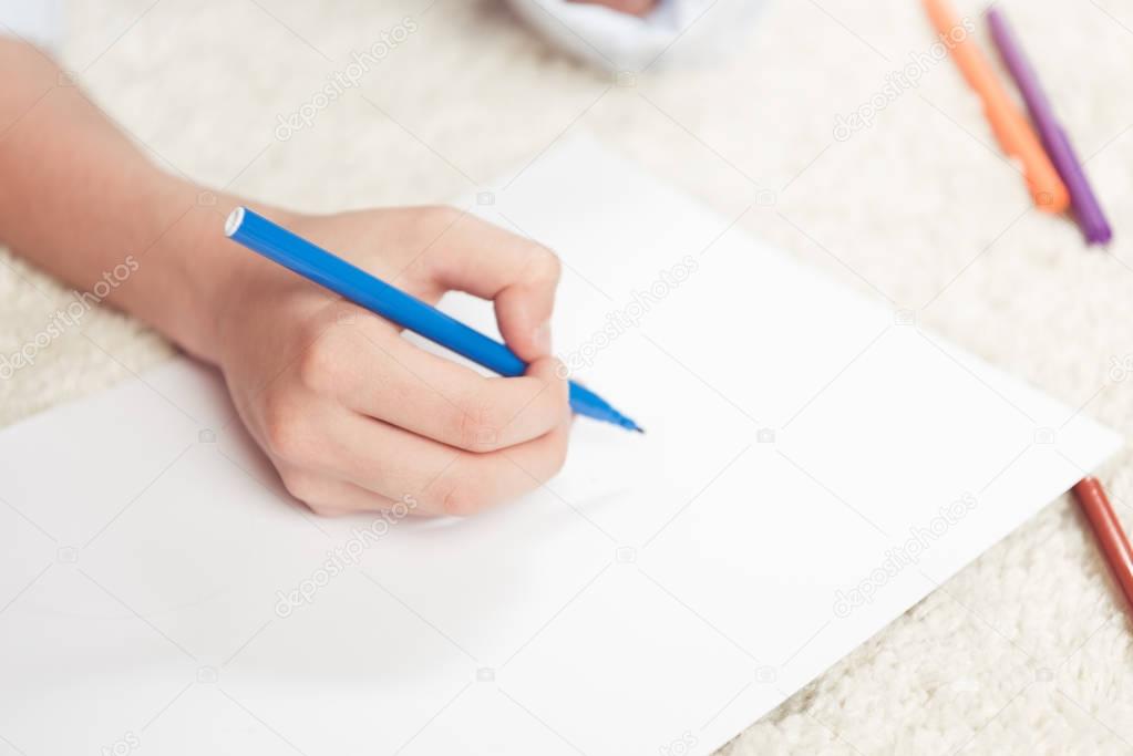 kid drawing with felt pen on paper