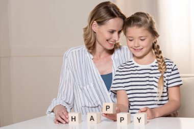 Girl and her mother using wooden cubes clipart