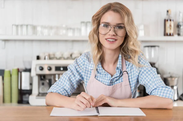 Barista writing in notebook — Stock Photo, Image
