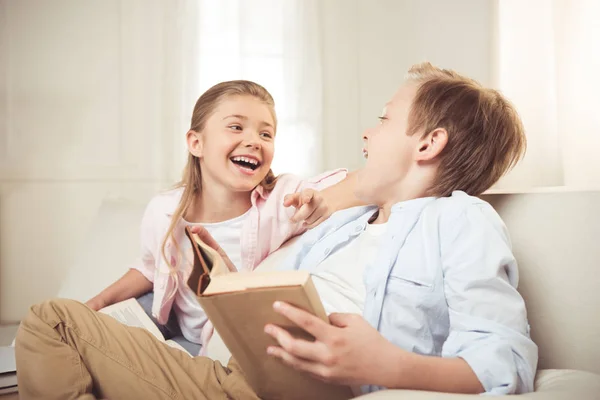 Hermanos leyendo el libro juntos - foto de stock