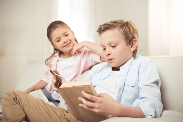 Hermanos leyendo el libro juntos - foto de stock