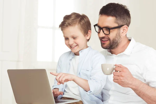 Padre utilizzando laptop con figlio a casa — Foto stock