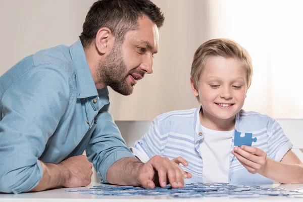 Hombre jugando puzzle con hijo - foto de stock