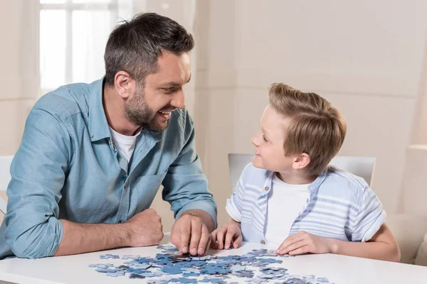 Hombre jugando puzzle con hijo - foto de stock