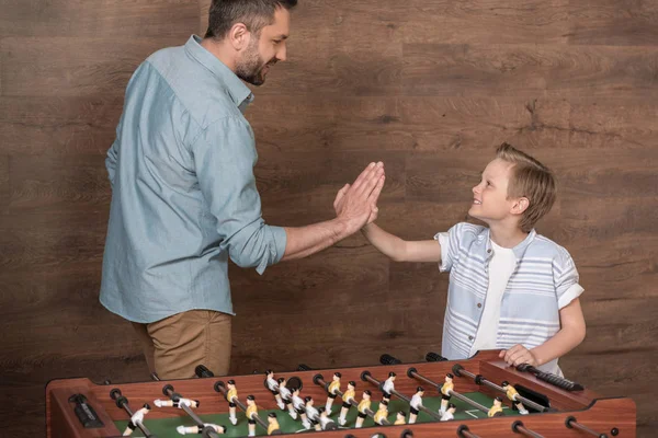 Chico jugando futbolín con padre - foto de stock