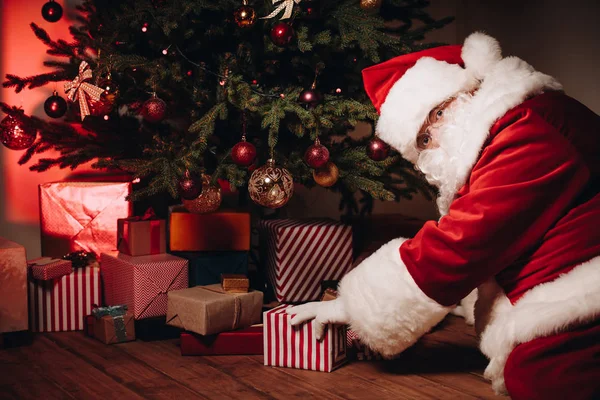 Санта с подарками под елкой — стоковое фото
