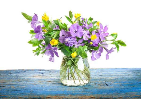 Spring flowers Periwinkle in glass vase on old wooden board — Stock Photo, Image