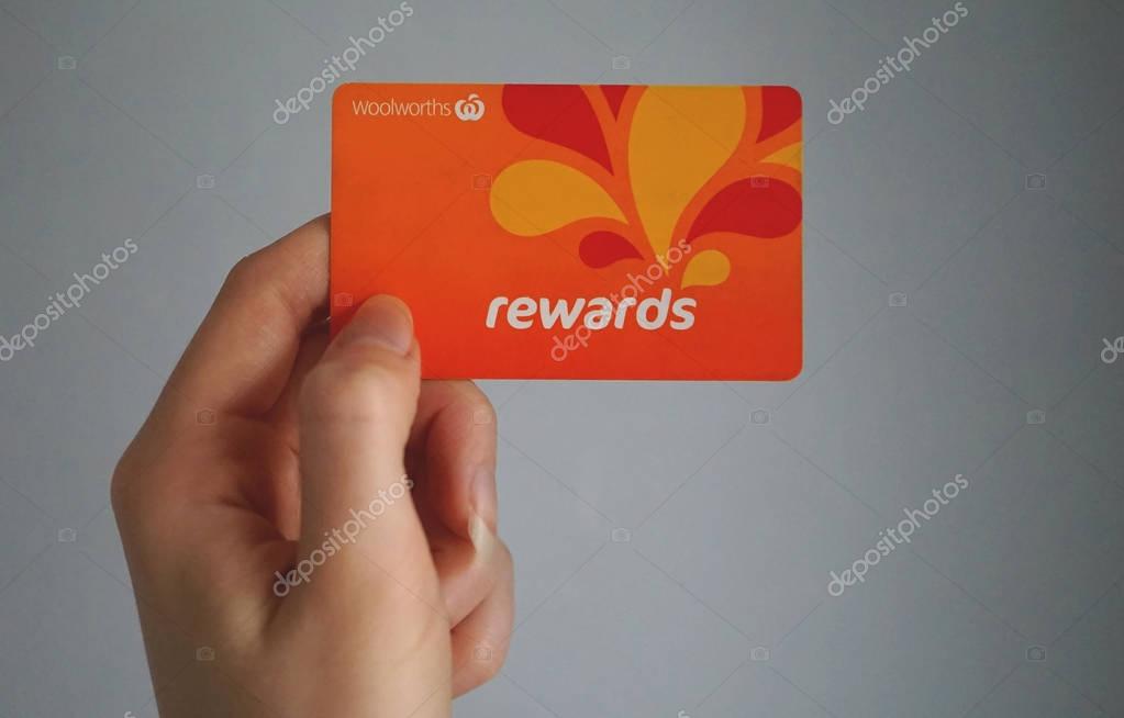 Sydney, Australia - October 15, 2017: Female caucasian hand is holding a Woolworths Rewards loyalty card, this loyalty program gives money off shopping. Woolworths Supermarkets is an Australian market leader grocery store chain.