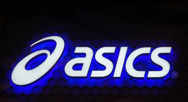 Logo Asics letrero de neón azul. Asics es una multinacional japonesa que produce calzado y equipamiento deportivo . — Foto de Stock