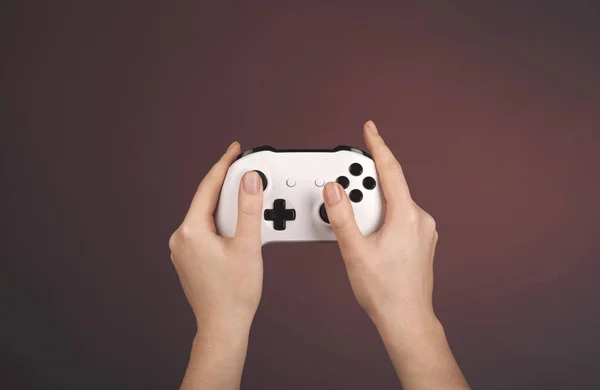 Τα χέρια κρατούν gamepad λευκό σε κόκκινο φόντο — Φωτογραφία Αρχείου