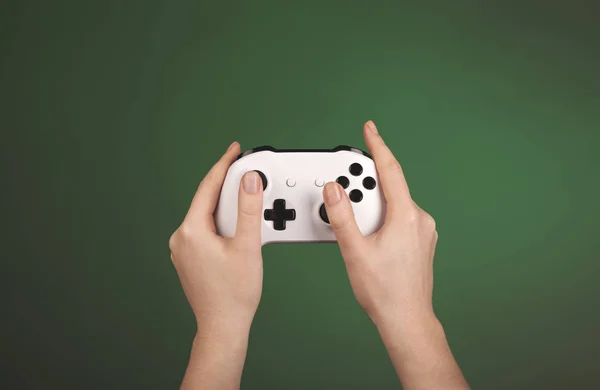 Τα χέρια κρατούν λευκό gamepad σε πράσινο φόντο — Φωτογραφία Αρχείου