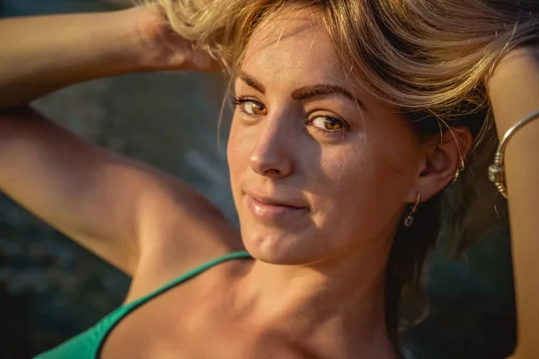 一个美丽的性感金发女郎穿着长绿松石站背景明亮的日落海滩上。特写肖像，性感的小女孩 — 图库照片