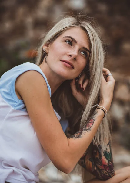 Красивая блондинка сидит на каменной набережной и читает книгу. Татуировка на руках. современный, модный, студент. Портрет крупного плана — стоковое фото