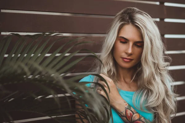 Portrait of a beautiful blonde closeup. Wearing a turquoise t-shirt. Arms tattooed. The concept of modern fashion. — Stock Photo, Image