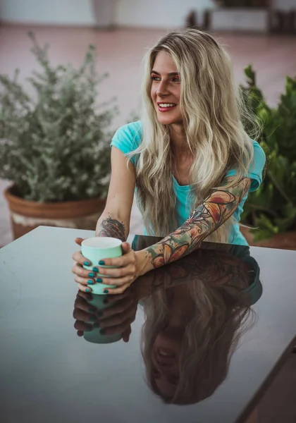 Retrato de uma linda loira com olhos expressivos. A segurar uma caneca de café. O conceito de cor turquesa. Mulher moderna — Fotografia de Stock